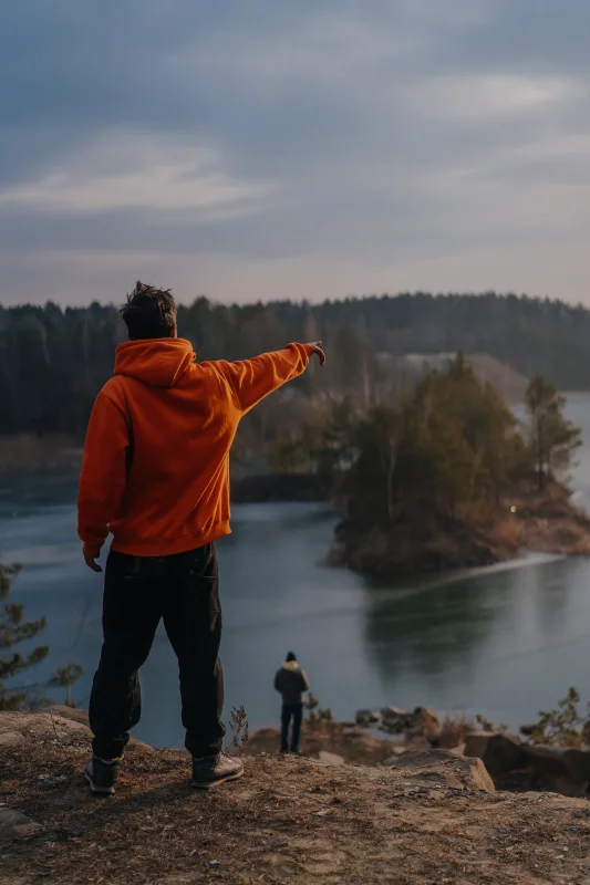 young-man-standing-edge-cliff-pointing